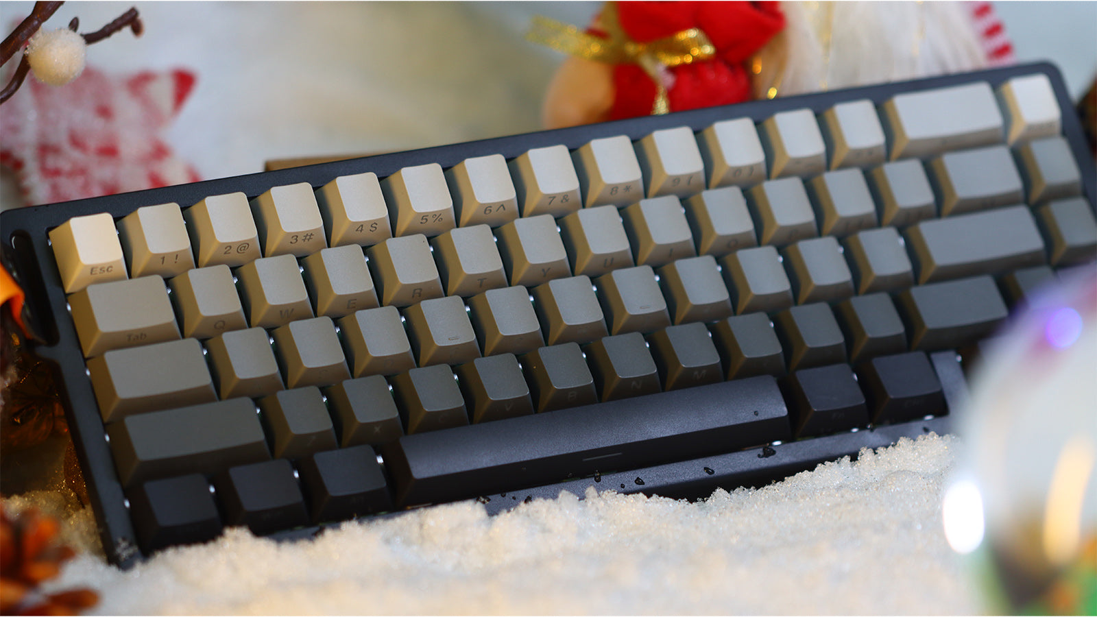 A magnetic keyboard with gray and white keycaps resting on a snowy surface