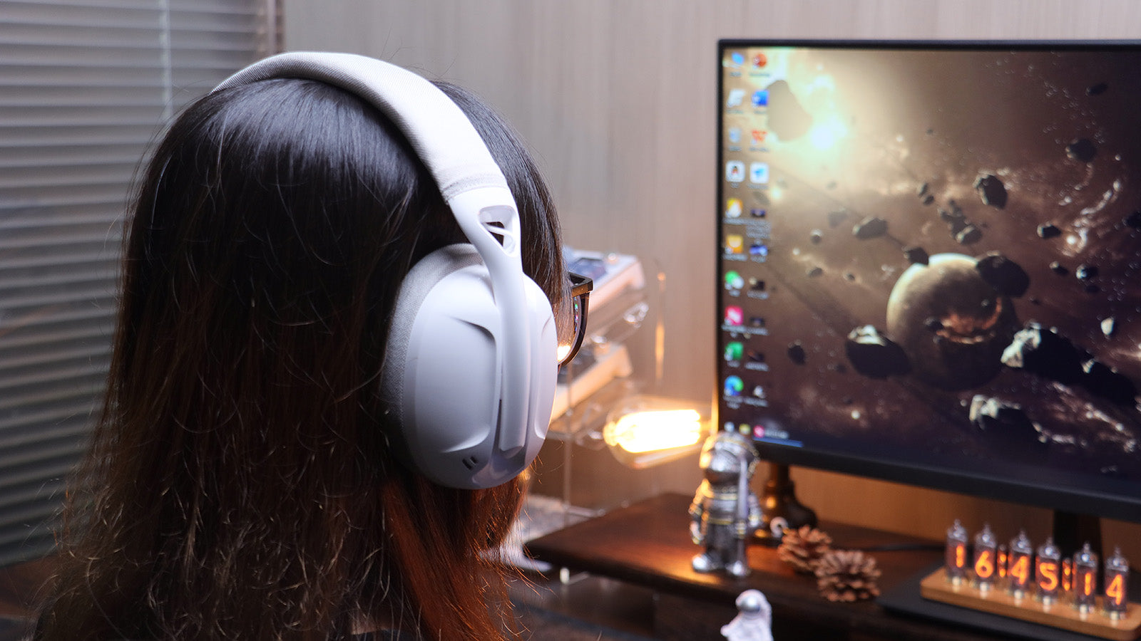 A person wearing a white gaming headset while sitting in front of a computer monitor. The headset has a padded headband and large earcups