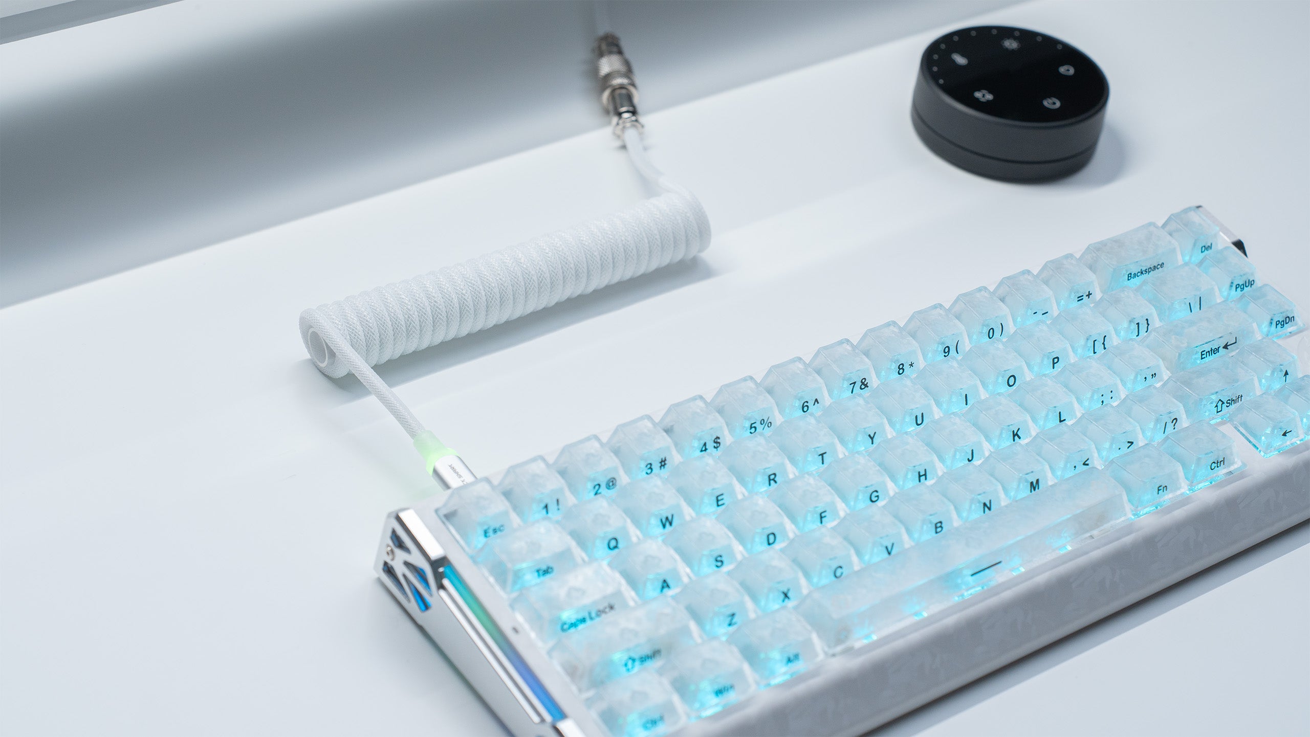 White coiled USB-C cable with stainless steel aviator connector beside a blue magnetic keyboard